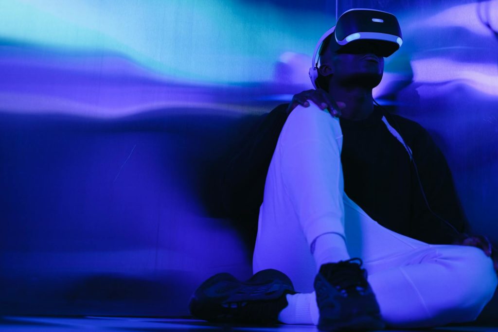 Man experiencing virtual reality in a colorful LED-lit room, wearing VR headset.
